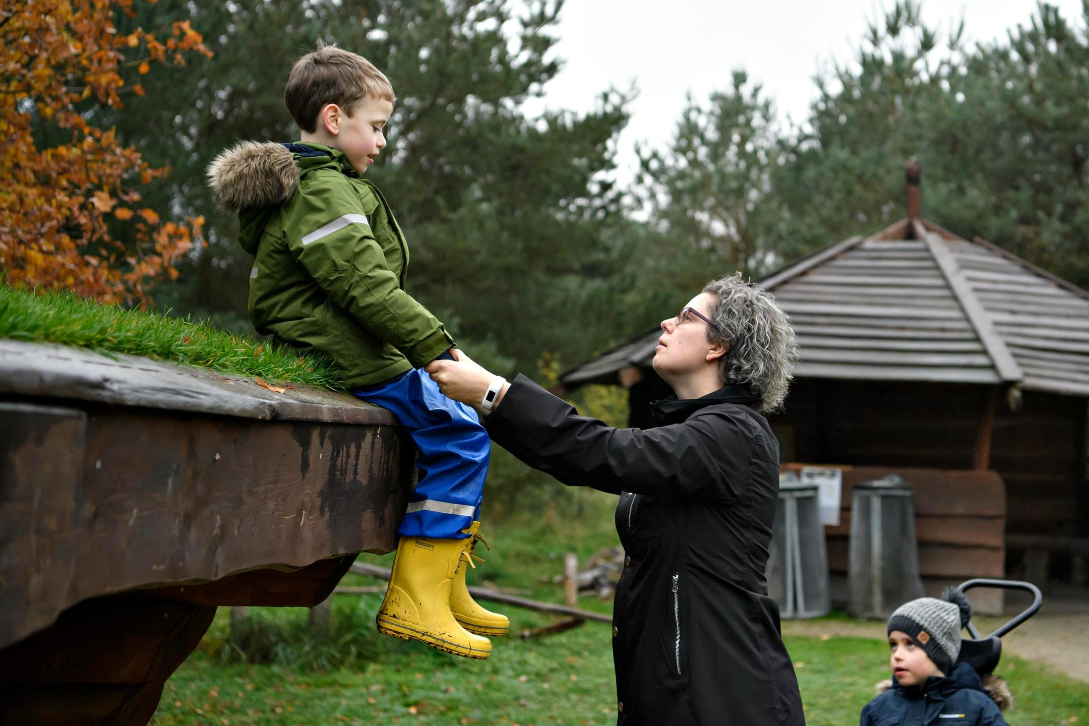 Barn sidder på sheltertag og holder i hånd med sin mor