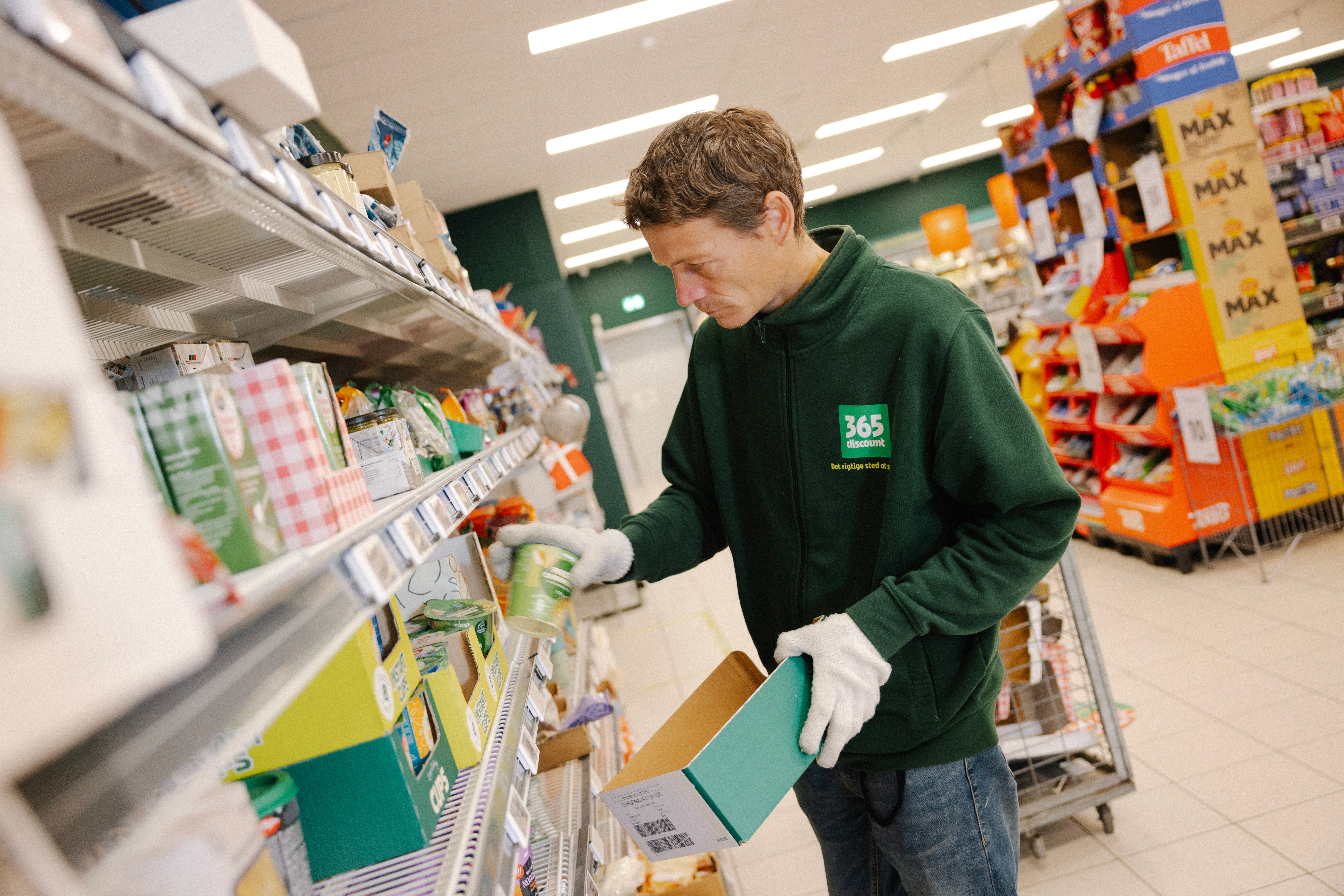 Mand står i et supermarked og fylder varer op