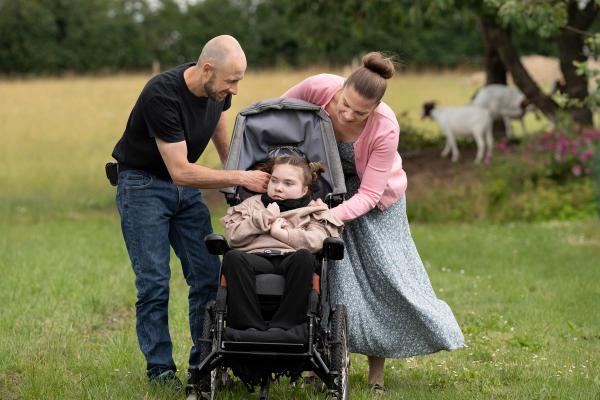 Forældre står på græsplæne med deres barn