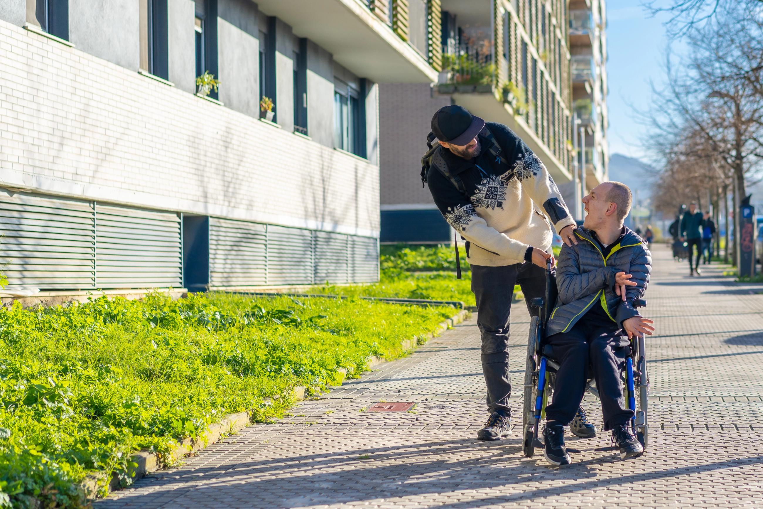 Ledsager hjælper en mand der sidder i kørerstol