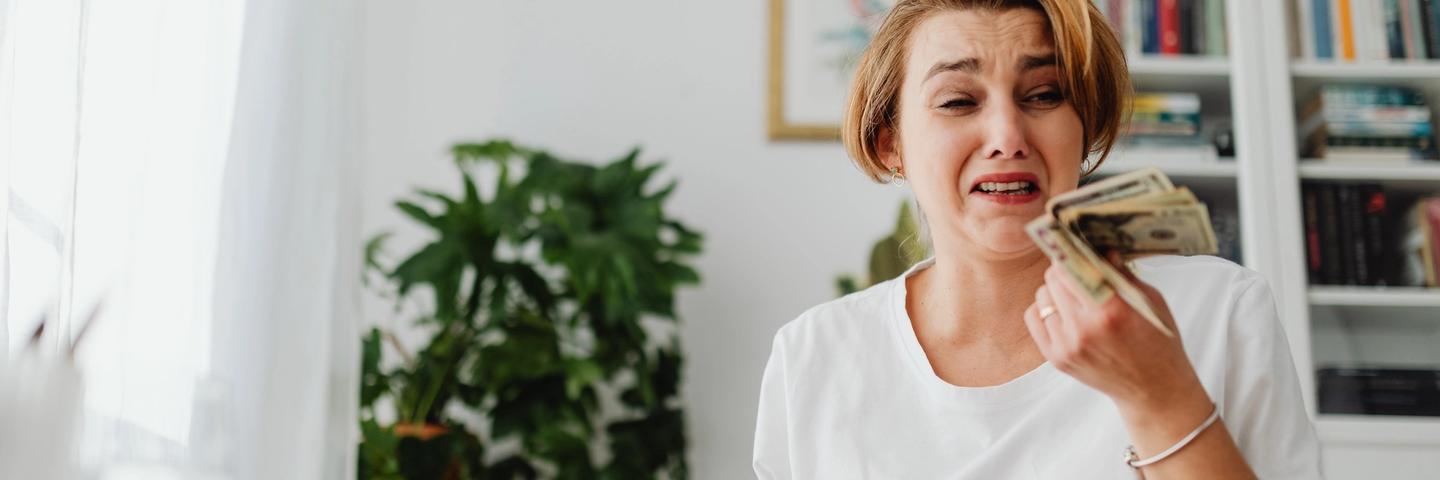 Une femme pleure en tenant de l'argent dans sa main