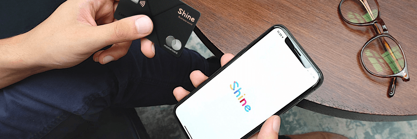 Un homme tient une carte bancaire Shine et l'application
