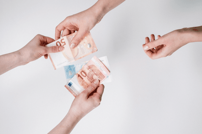 Deux mains qui s'échangent des billets en euro