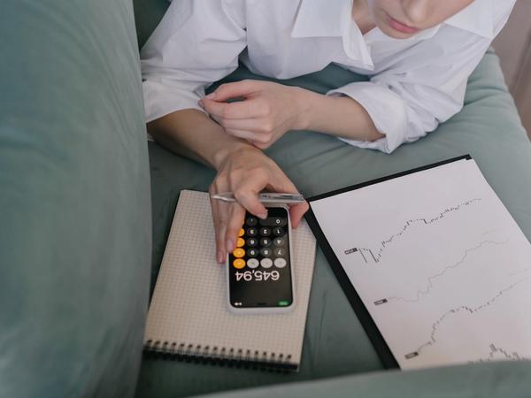 Une femme calcule des frais sur une calculatrice