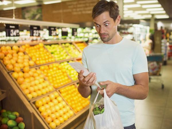 Un homme regarde son ticket de caisse pour faire des économies sur les courses