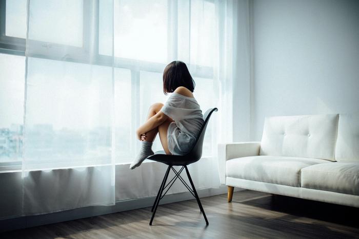 Une femme assise devant une fenêtre