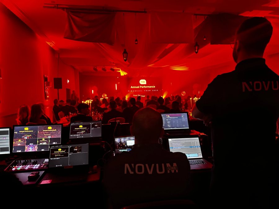 Large event venue during setup, showing staging, lighting rigs, screens and professional AV control equipment