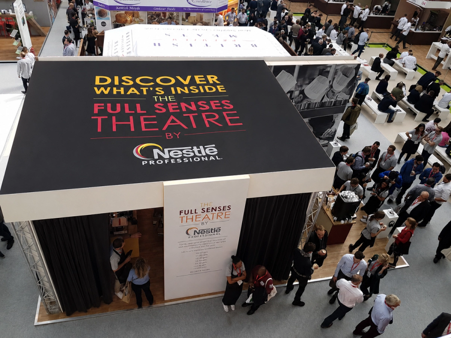 A busy exhibition floor featuring a large branded Nestlé Professional ‘Full Senses Theatre’ activation, surrounded by delegates networking and engaging with the experience.
