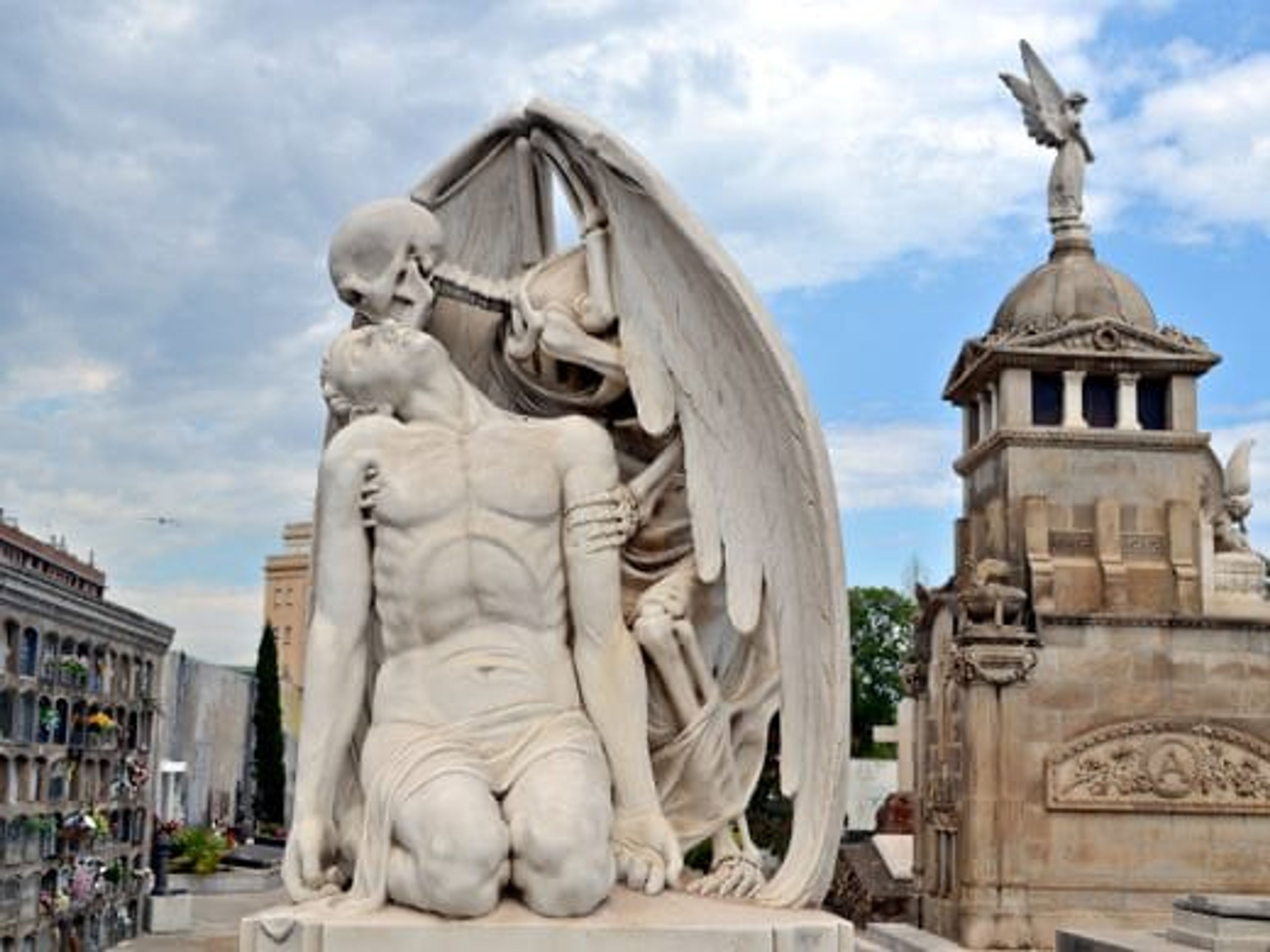 A skeleton angel kissing a dying human in statue form