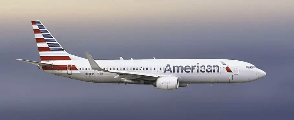 A white plane with American's logo flying through the air