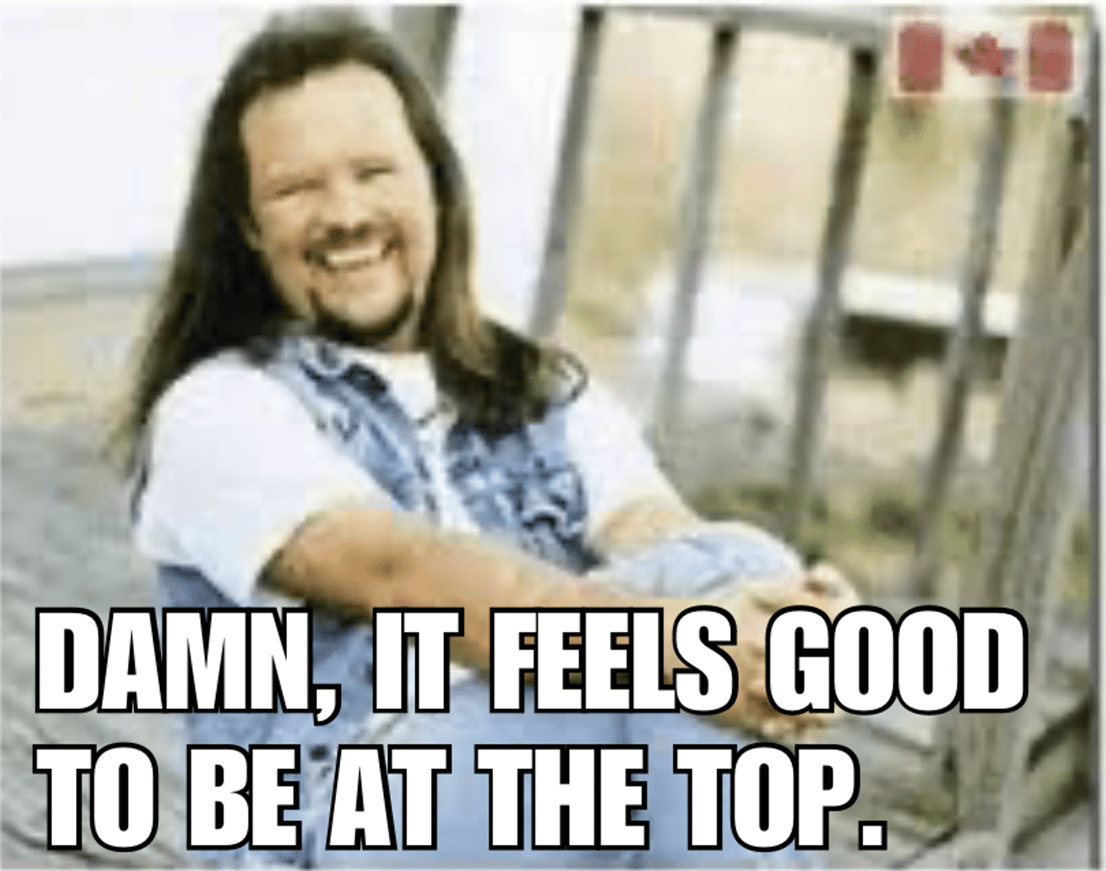 A man laughing with text overlay: "Damn, it feels good to be at the top."