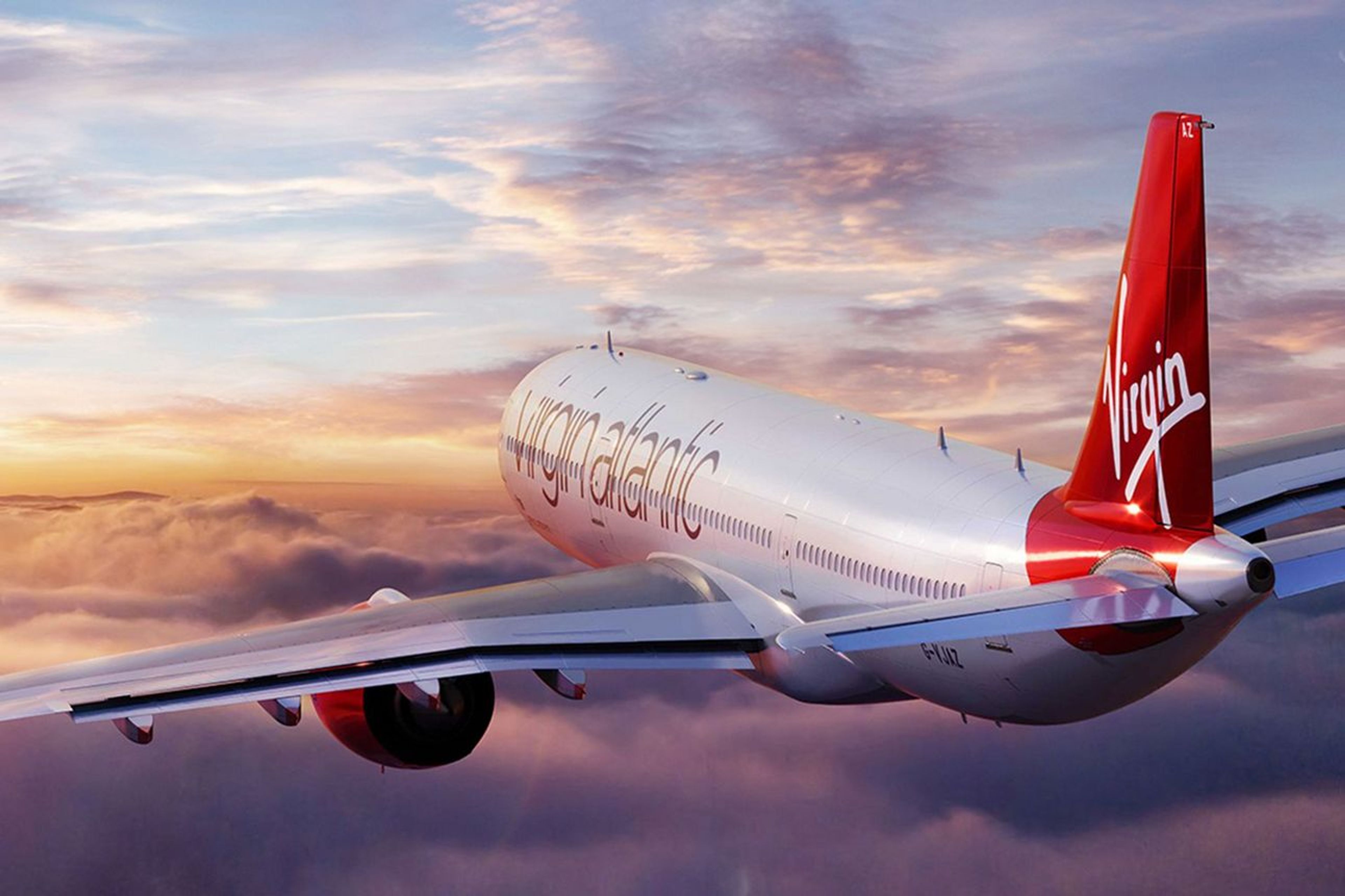 A Virgin Atlantic plane flying above the clouds at sunset