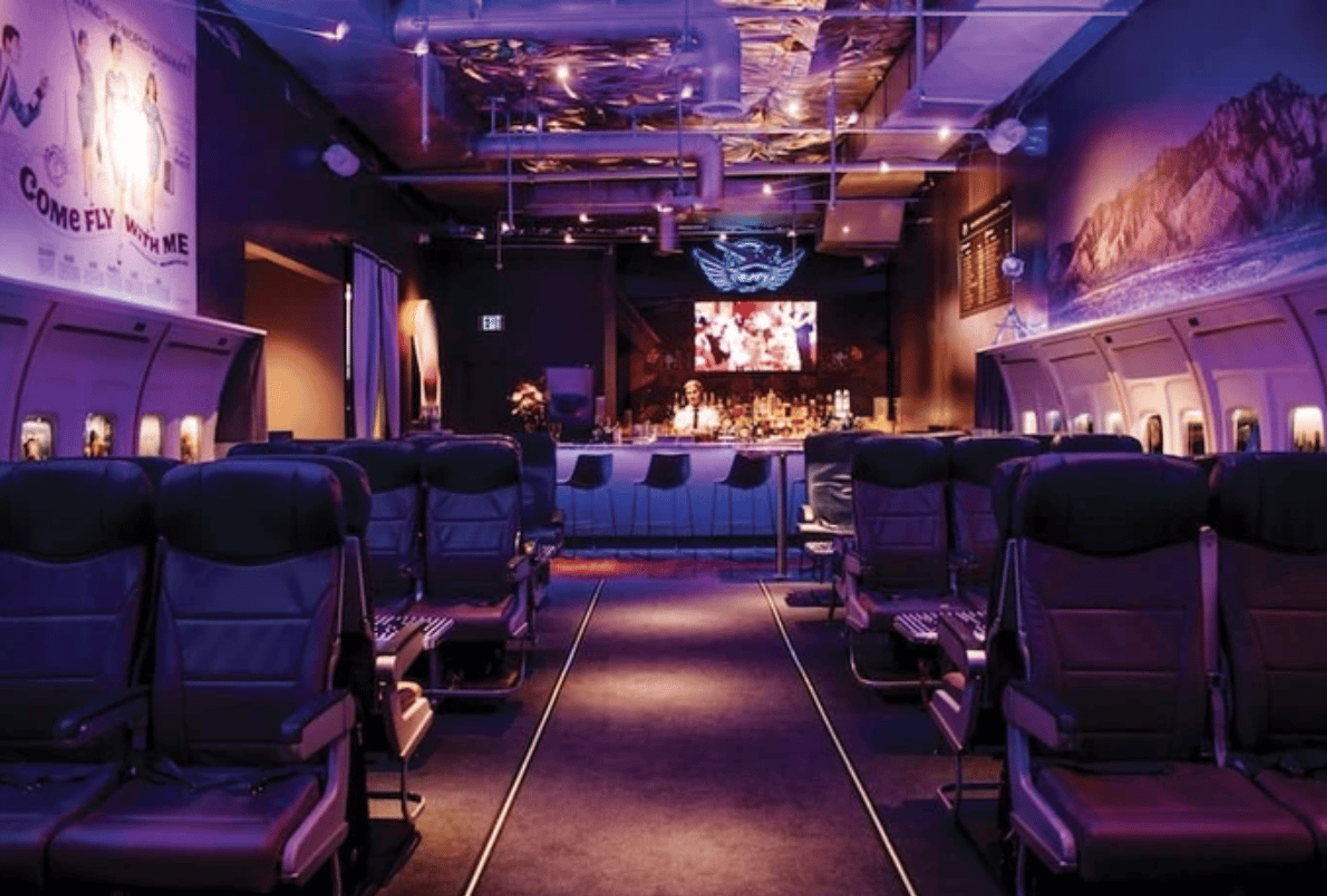 Interior of PS Air Bar with purple lighting, airplane seats, and a bar in the back