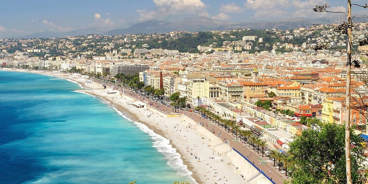 A coastal promenade with blue water and buildings in the background
