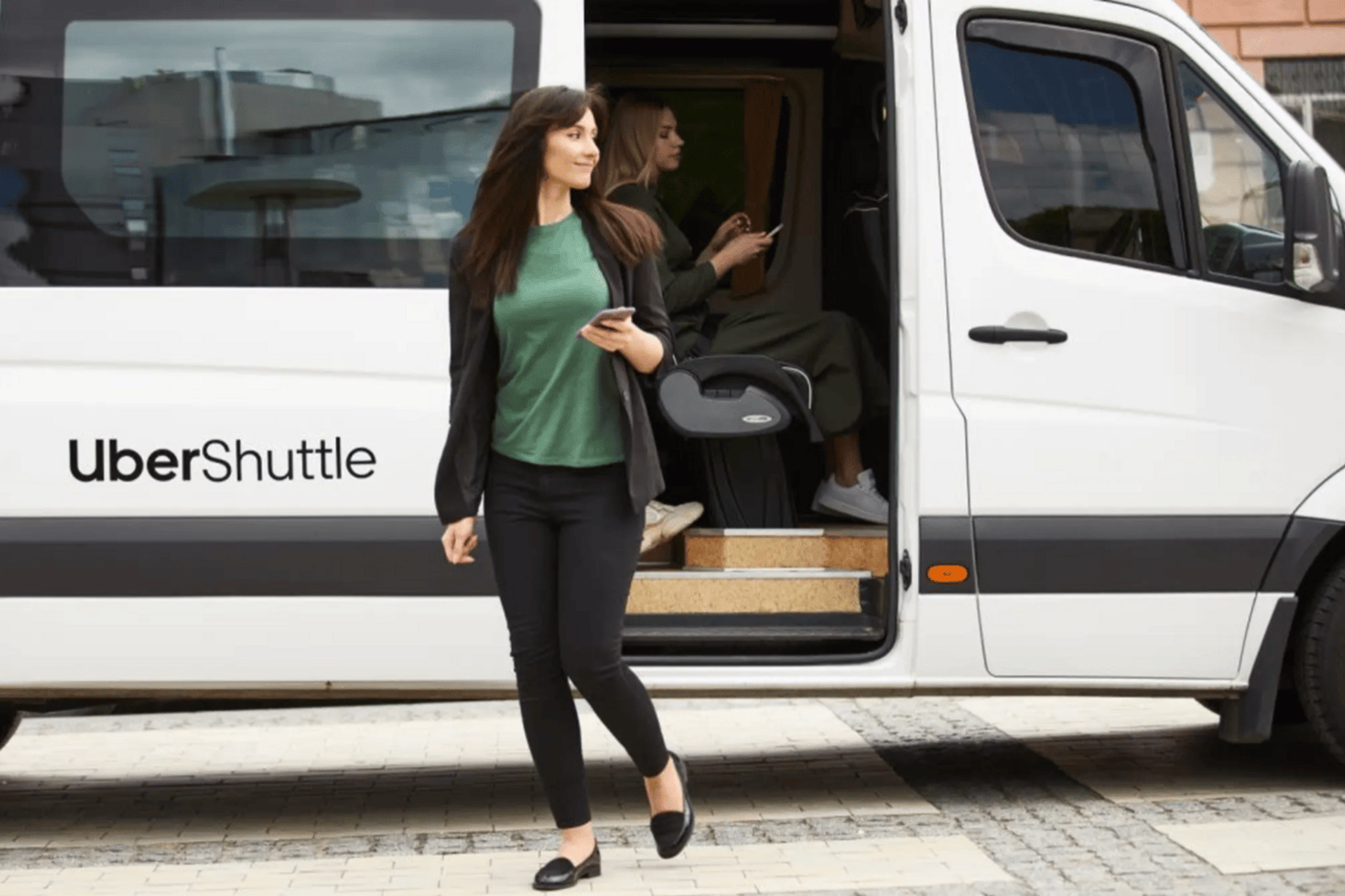 A woman stepping out of a white sprinter van as an Uber Shuttle