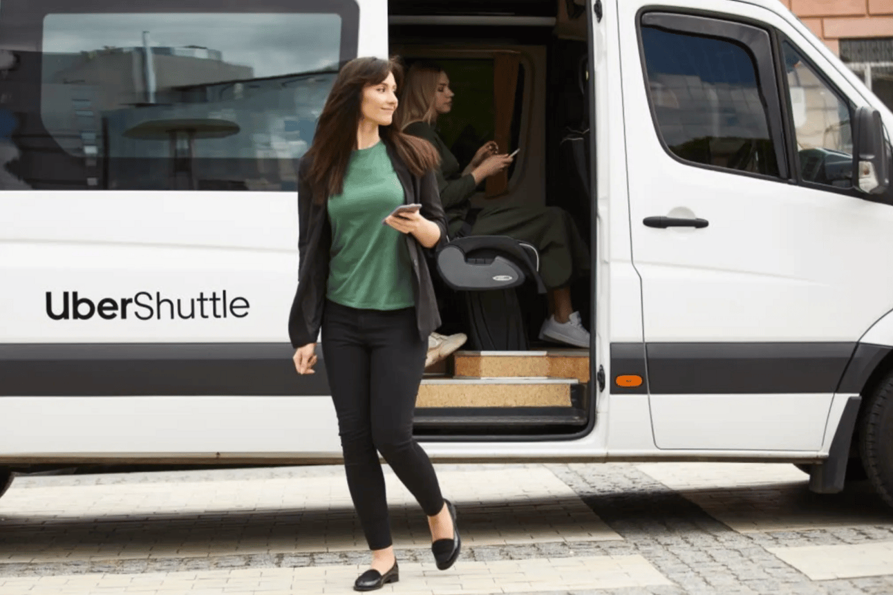A woman stepping out of a white sprinter van as an Uber Shuttle