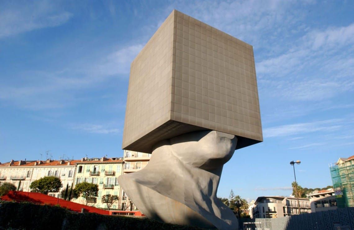 A sculpture of a head with a massive block