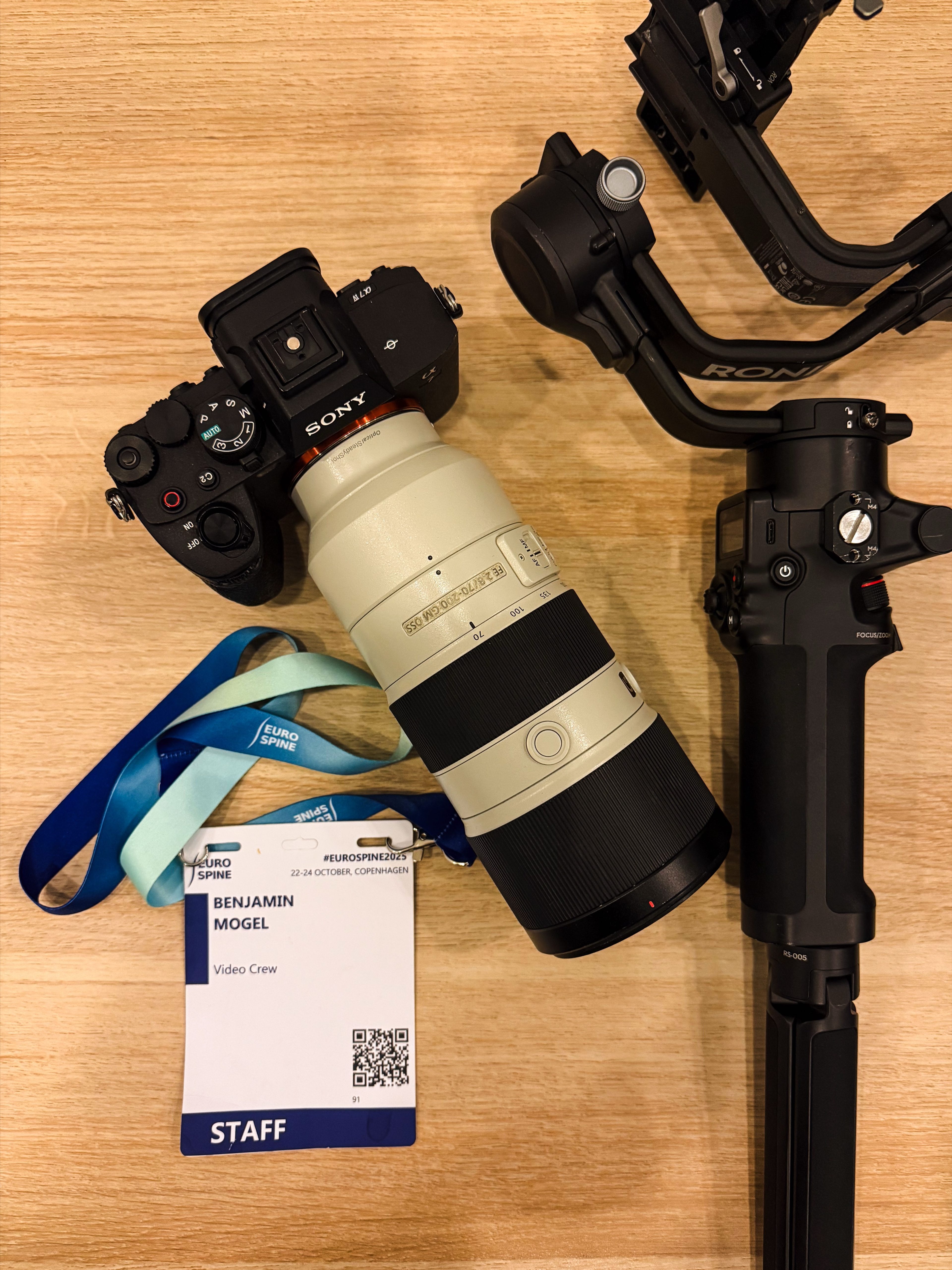 Camera, telephoto lens, gimbal and staff badge laid out before filming