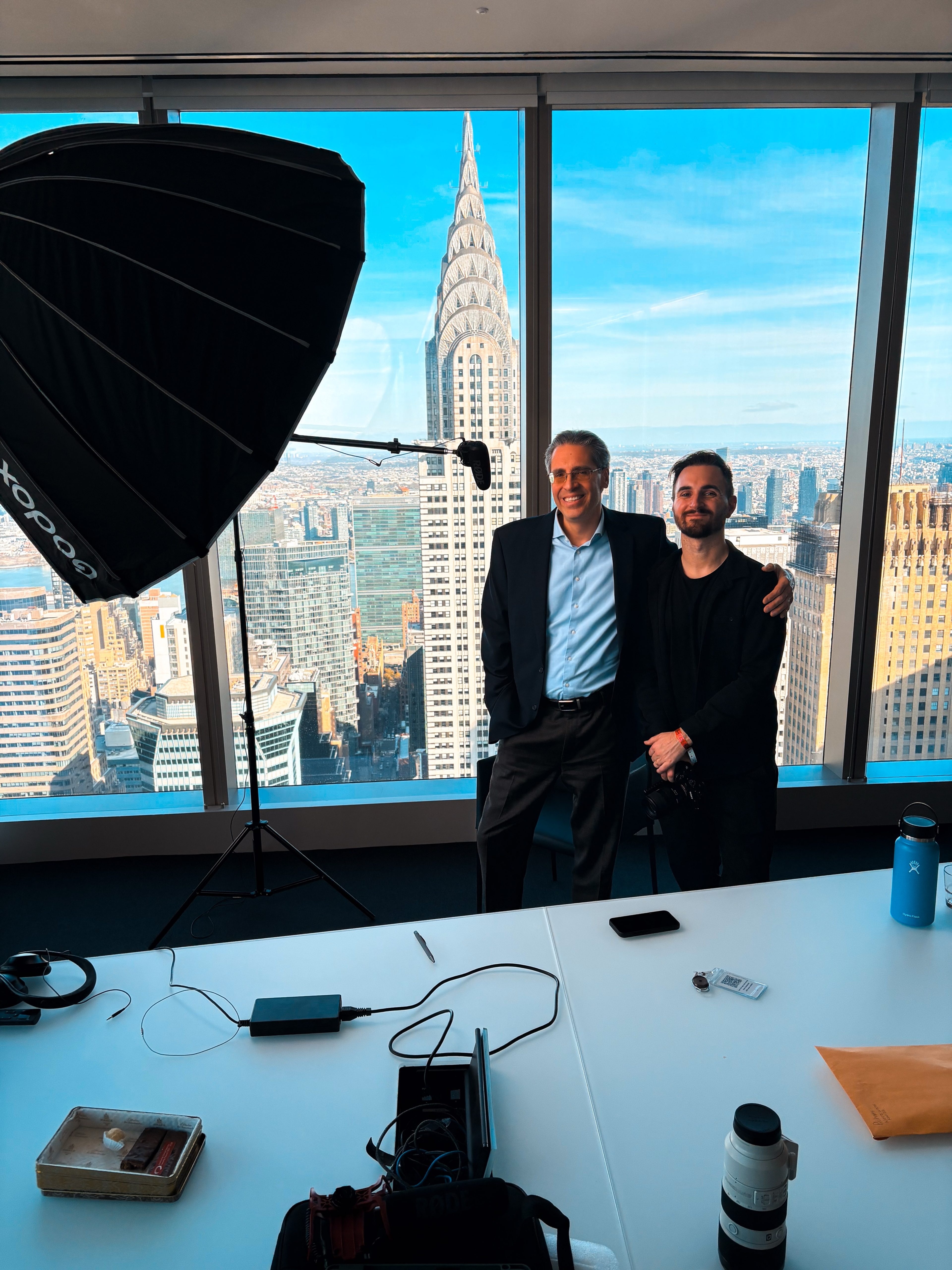 Two people by the window beside the lighting setup, Chrysler Building behind