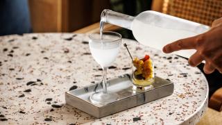 Hånd som sjenker iskald dry martini fra frossen flaske i et glass.
