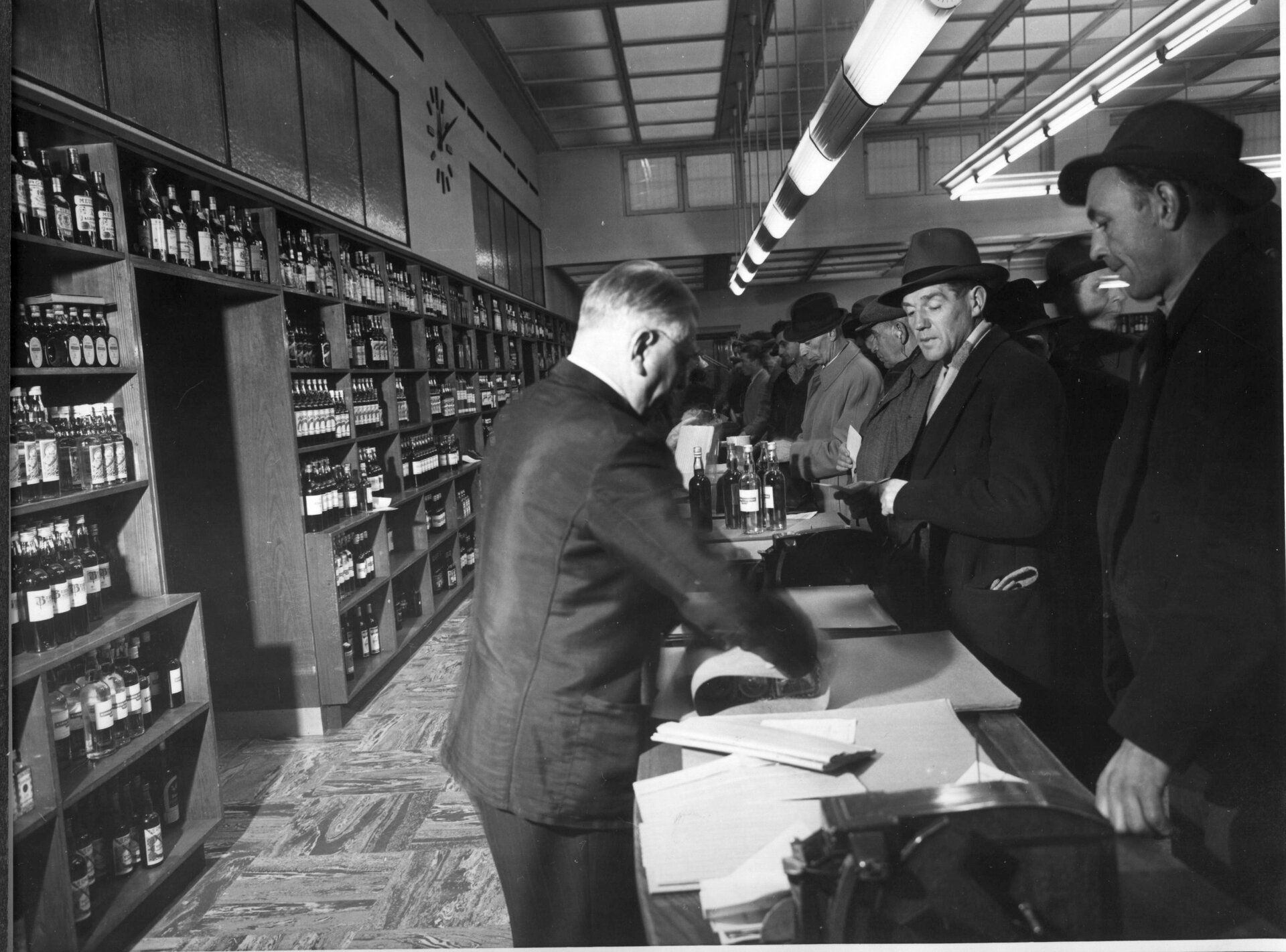 Mennesker som står i kø og ansatte bak disken på polet i Storgata i 1953.