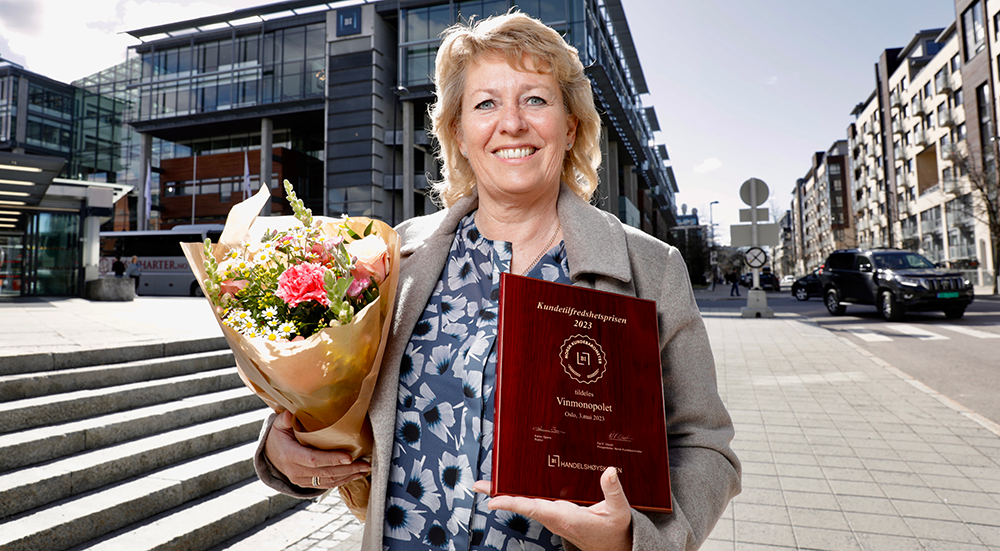 Administrerende direktør Elisabeth Hunter som smiler med prisen og en blomsterbukett i hendene.