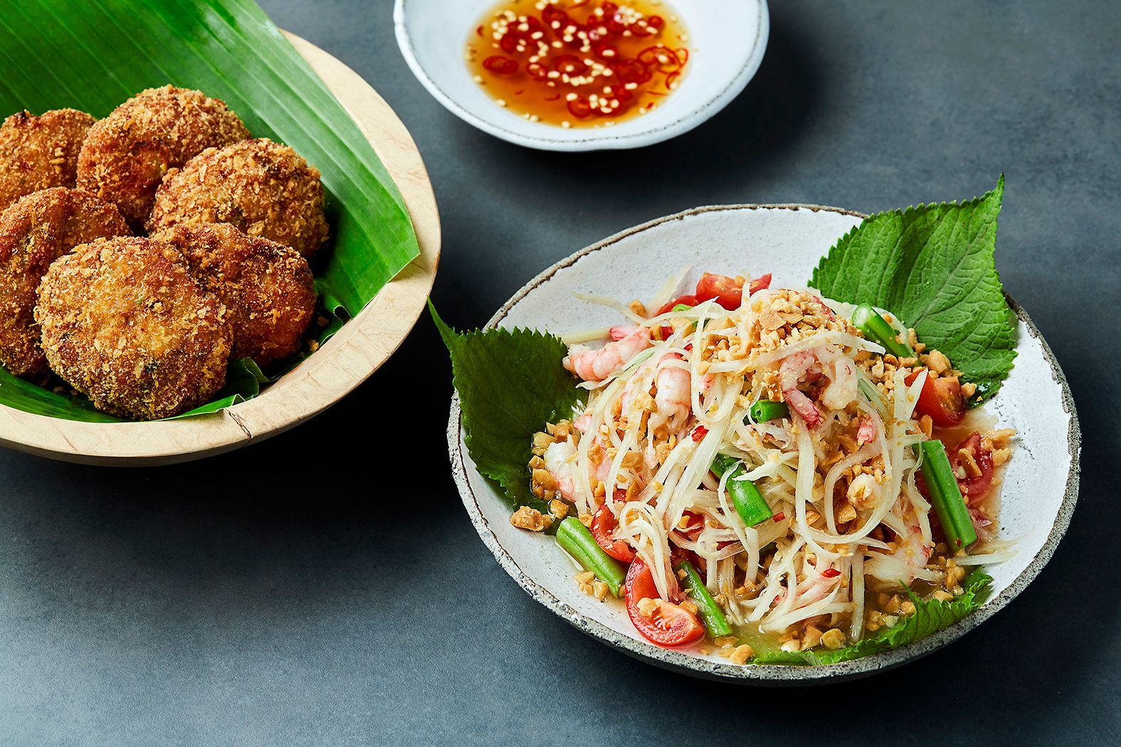 Skål med papayasalat med reker og skål med thailandske fiskekaker