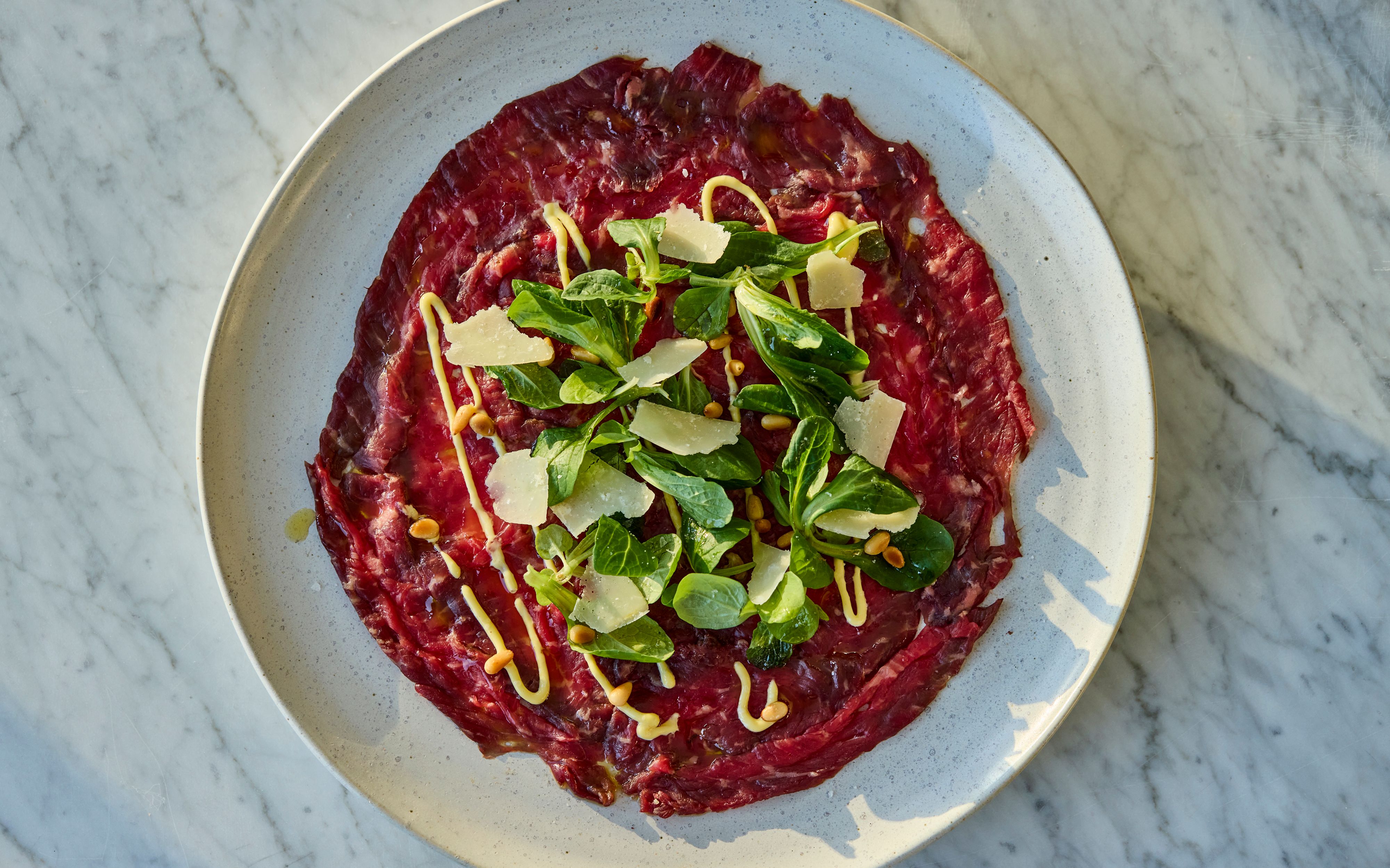 Carpaccio av rått oksekjøtt med salat og parmesan.