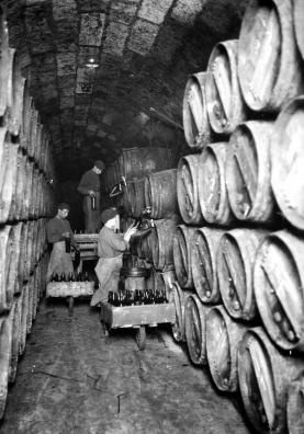 Arbeidere tapper flasker med vin rett fra fatene.