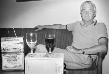 Salgsdirektør Egil Sveine som sitter i en sofa med pappvin og vinglass foran seg i 1988.