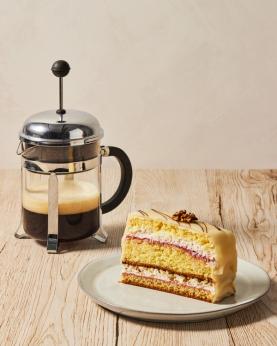 En presskannne med bokøl og et kakestykke på en asjett.