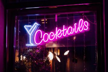 Neonskilt i barvindu med martiniglass og cocktail.