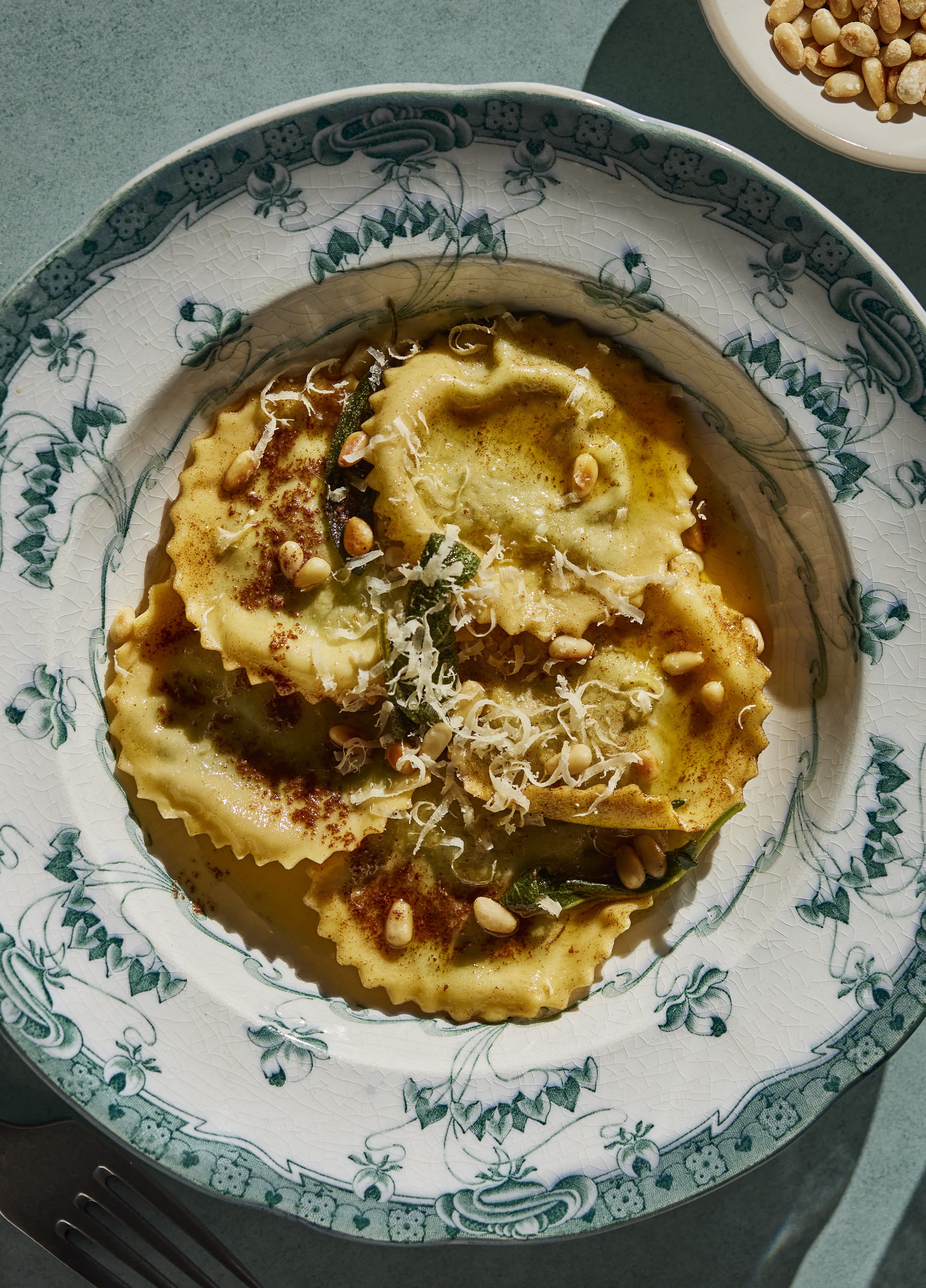 Tallerken med fylte pastaputer, urtesmør, pinjekjerner og revet ost.