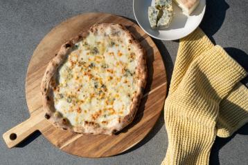 pizza med fire oster på en trefjøl.