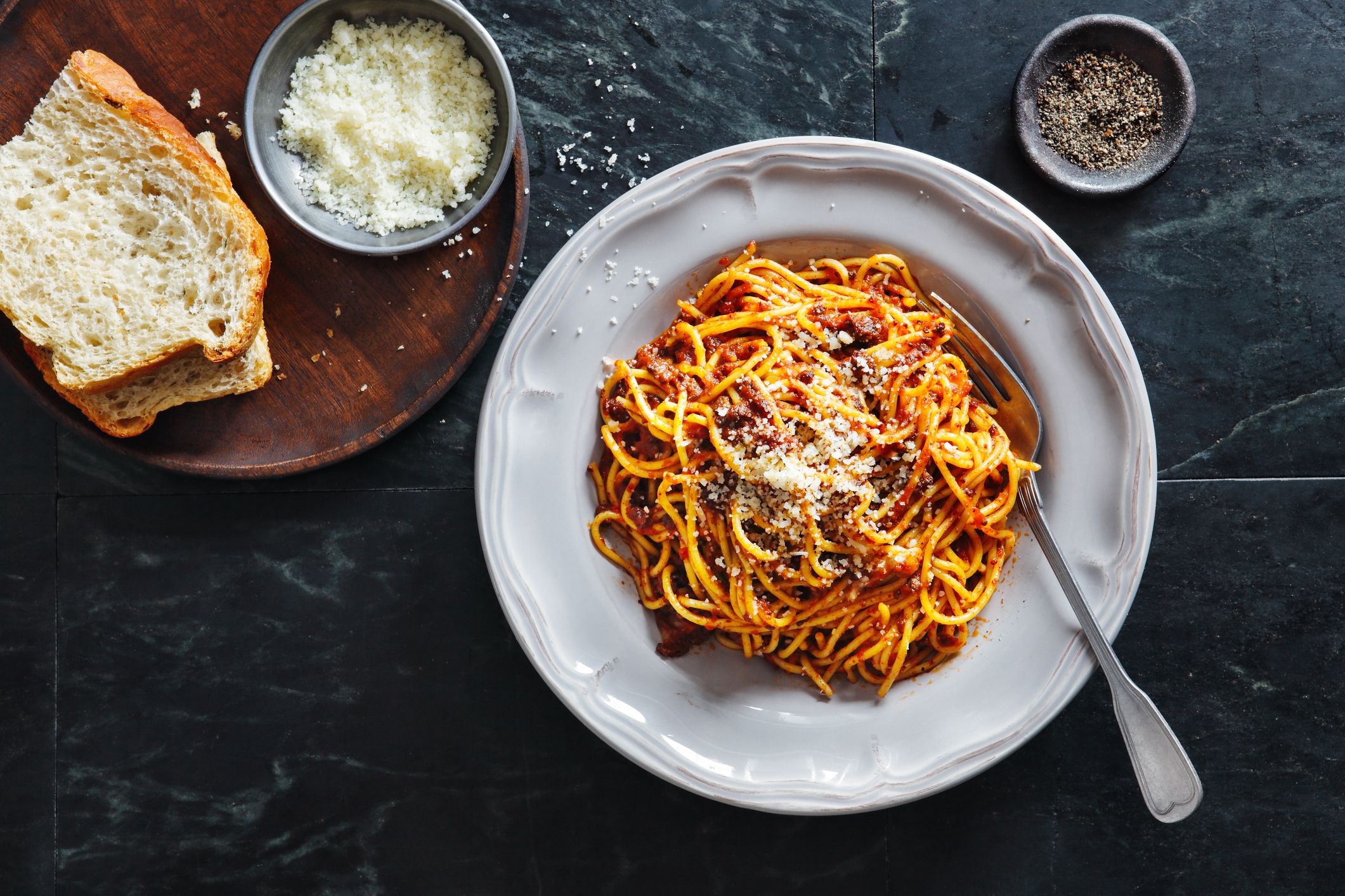 skål med pasta bolognaise, parmesan og brød på siden.