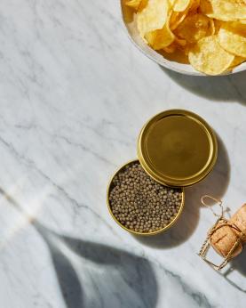 En boks med størkaviar, champagnekork og skål med chips.