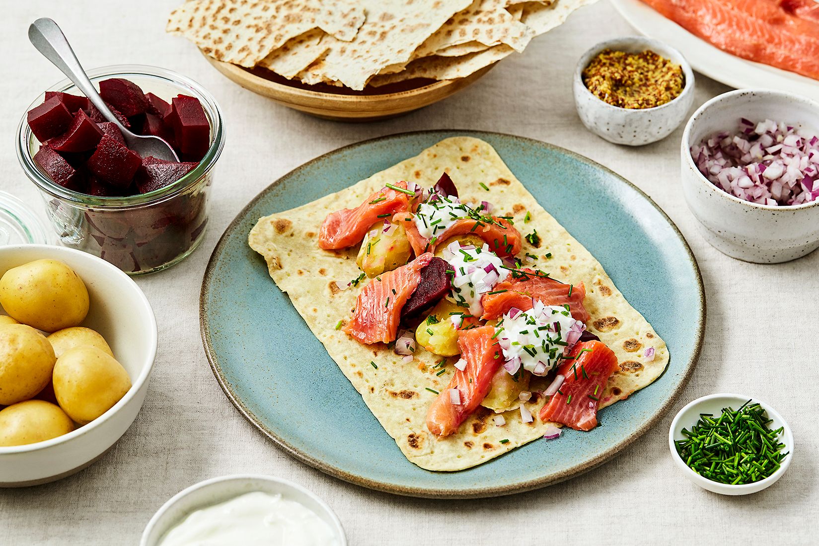 Tallerken med lefse fylt med rakfisk, potet, løk og rømme.