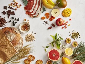 Bord med råvarer som illustrerer aromaer i ulike ølstiler, Brød, korn, kaffe, frukt.