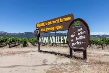 Velkomstskilt til Napa Valley med vingård i bakgrunnen.