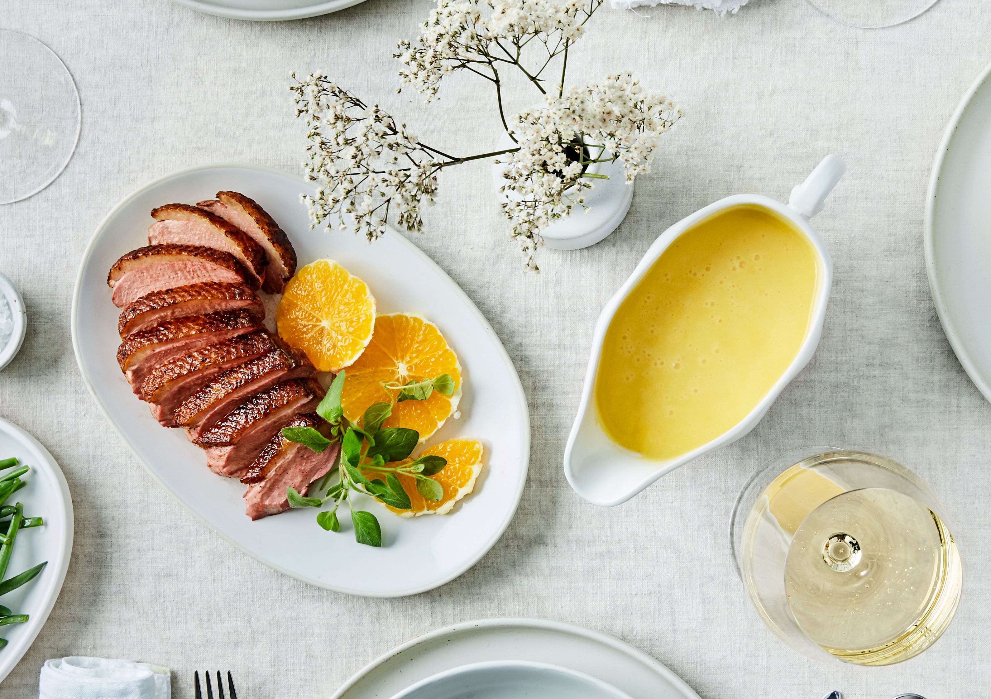 skål med appelsinsaus og fat med stekt andebryst og appelsinskiver.