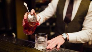 bartender som heller negroni i et glass.