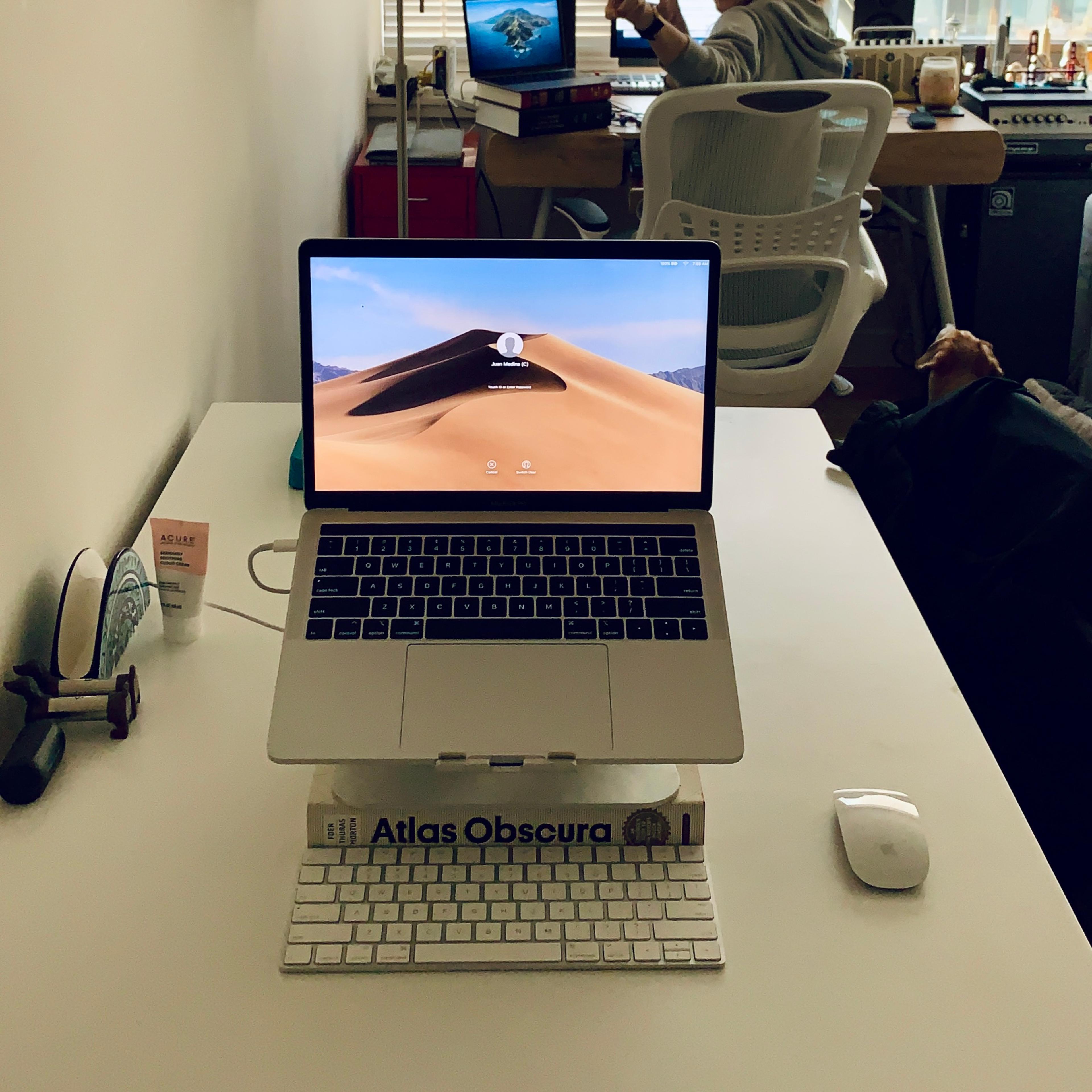 A laptop with an external mouse and keyboard over a white dining table