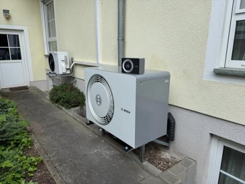 Außeneinheit einer Bosch-Wärmepumpe mit Bedieneinheit entlang eines Hauswegs