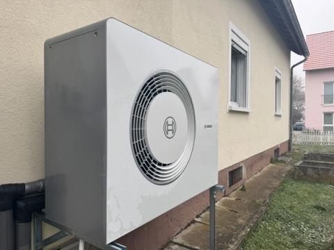Große Außeneinheit einer Bosch-Wärmepumpe an der Seitenwand eines Wohnhauses