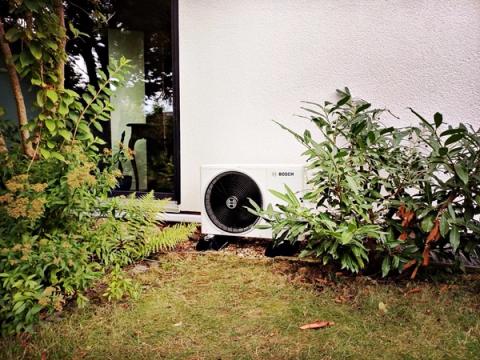 Bosch-Außengerät einer Klimaanlage vor einer weißen Hauswand im Garten