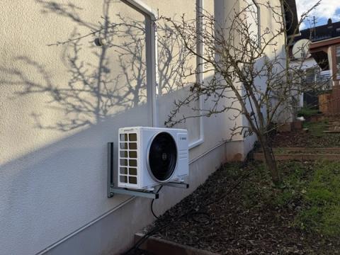 Außengerät einer Klimaanlage auf einer Wandkonsole an einer sonnigen Hauswand