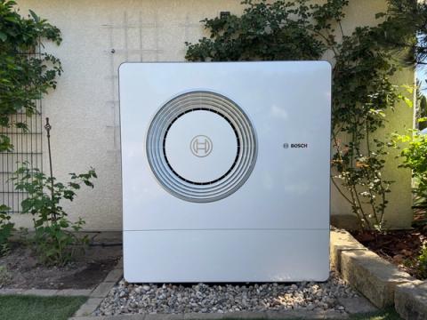 Große Außeneinheit einer Bosch-Wärmepumpe vor einer bewachsenen Hauswand