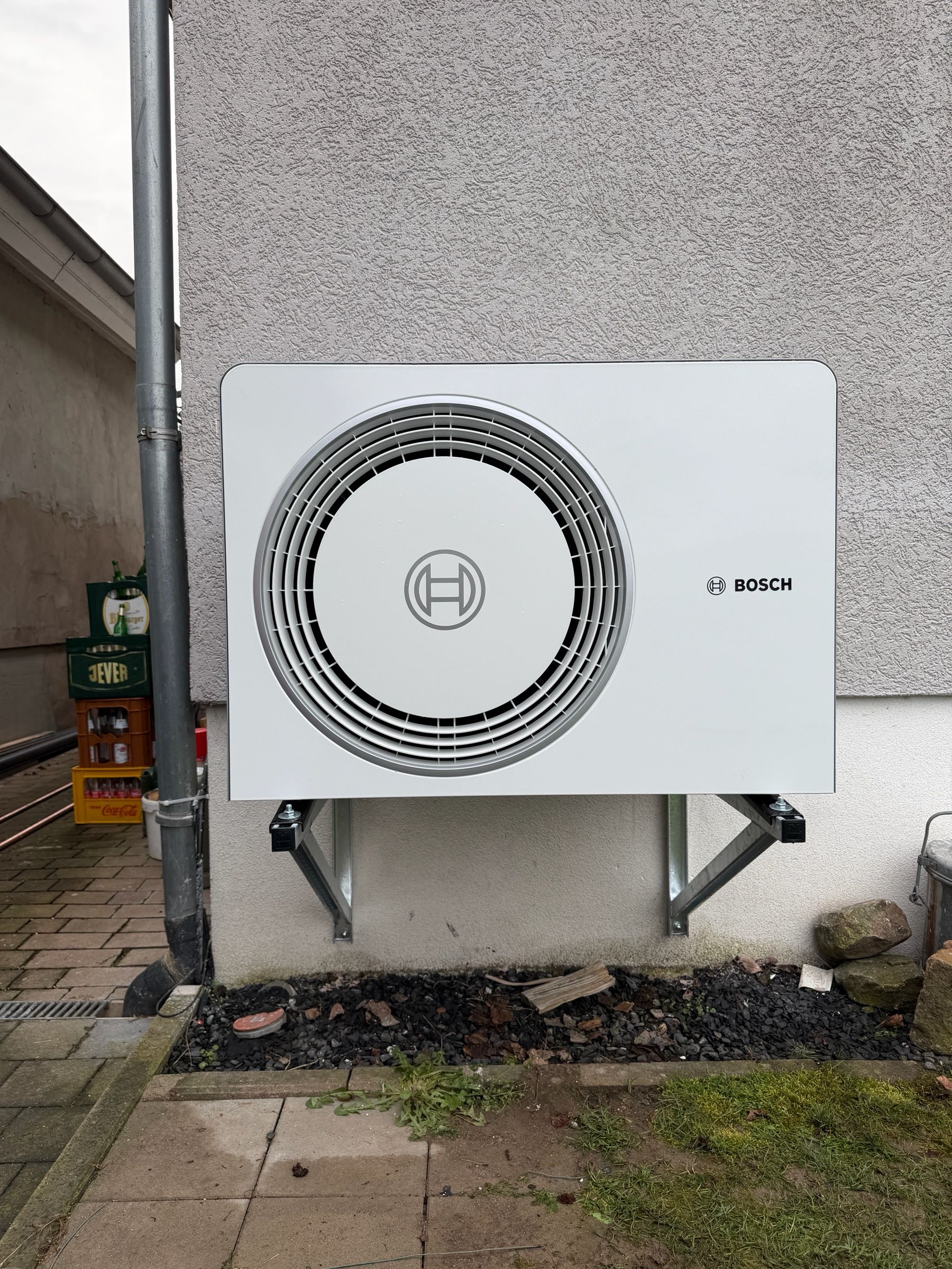 Außeneinheit einer Bosch-Wärmepumpe auf einer Wandkonsole an einer grauen Hauswand