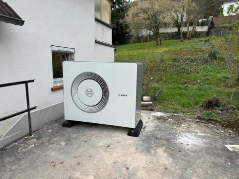 Außeneinheit einer Bosch-Wärmepumpe auf einer Terrasse vor einem Garten