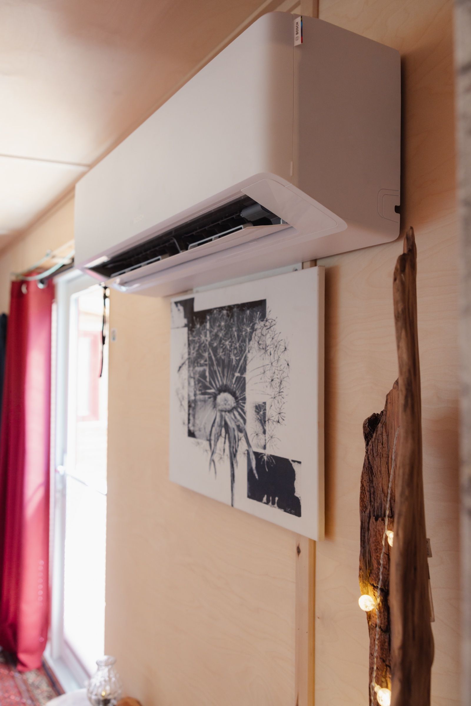 Weißes Innengerät einer Klimaanlage an einer holzverkleideten Wand über einem Bild